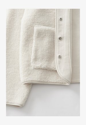Giacca in pile color crema con superficie morbida e testurizzata, tasca laterale e bottoni a pressione argentati lungo l'apertura frontale.