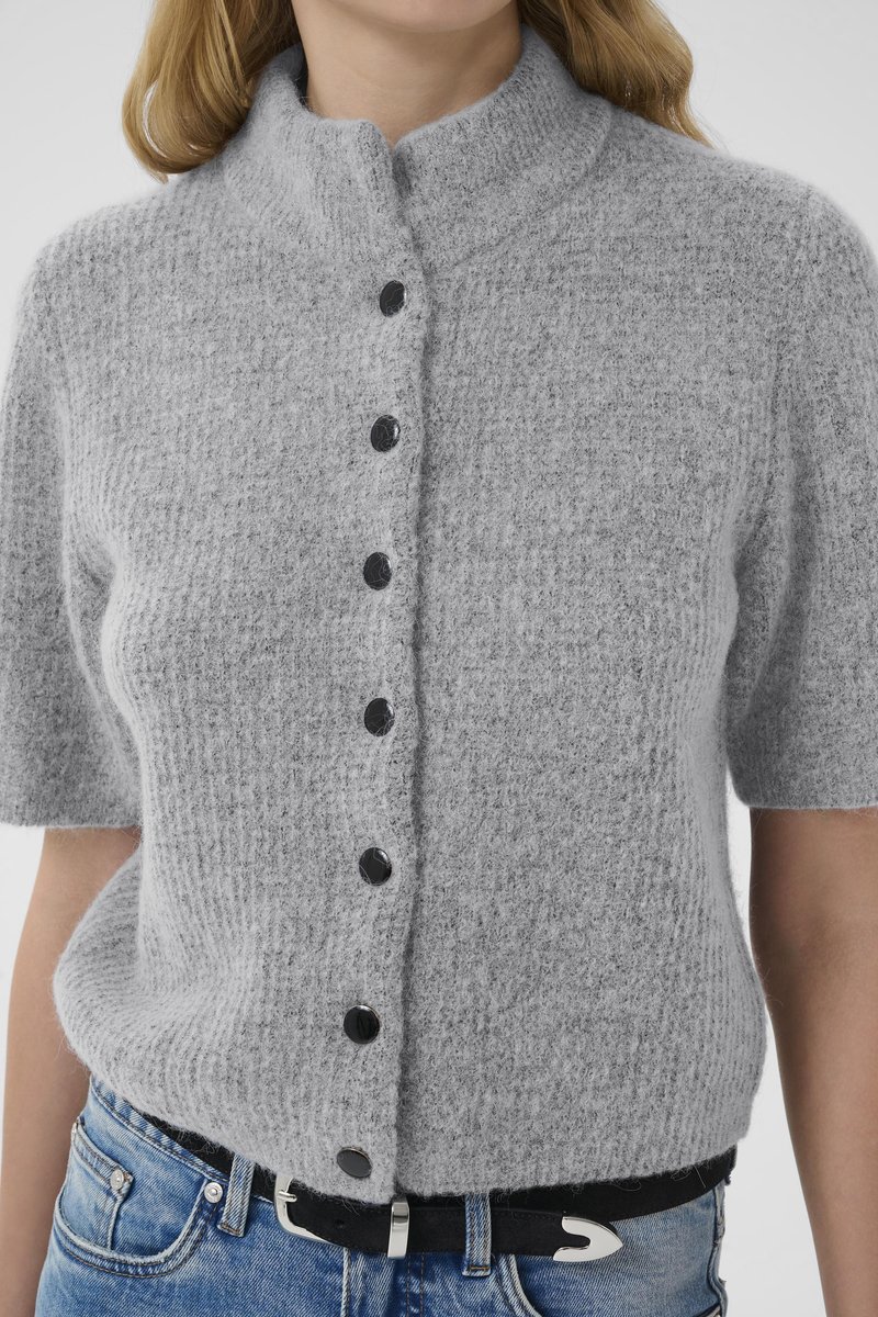 Gray knit button-up sweater with short sleeves, featuring a high neck and six black buttons; worn over denim with a black belt.