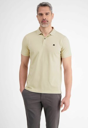 Licht kaki poloshirt van katoen, met een kraagontwerp, korte mouwen en een klein zwart logo op de linkerkant van de borst. Gecombineerd met grijze broeken.