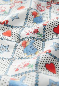 Baumwollstoff mit einem bunten Cartoon-Bären in einem blauen Mantel, umgeben von Herzen, Blumen und Sternmustern auf weißem Hintergrund.