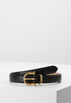 Czarny skórzany pasek z zakrzywioną złotą klamrą i złotą pętlą, wyeksponowany zwinięty na białej powierzchni na jednolitym tle.