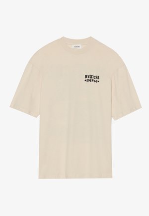 Kermanvärinen puuvillapaita, jossa on lyhyet hihat ja rento leikkaus. Vasemmassa rinnassa on musta graafinen teksti "MYSTICAL ENERGY".