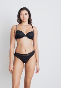 Black lingerie set featuring a padded bra with adjustable straps and matching high-waisted briefs with lace accents. Smooth fabric texture.
