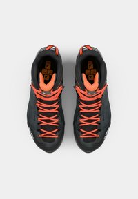 Black high-top climbing shoes with bright orange laces, padded tongue, textured rubber sole, and reinforced toe cap for durability.