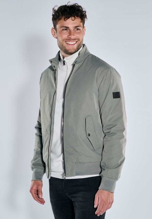 Hellgraue Bomberjacke aus glattem Stoff, mit Reißverschluss vorne, Stehkragen, vorderer Tasche und elastischen Bündchen.