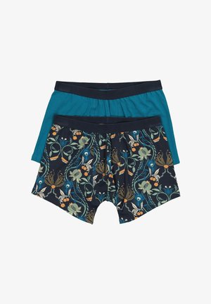 To herre-bokserbriefs, en ensfarvet teal blå og en marineblå med flerfarvet blomstermønster og frugt, begge med sorte taljebånd.