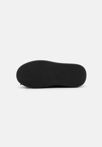 Black rubber shoe sole with a textured surface, featuring a pattern of small squares and ridges for grip. Smooth edges with rounded toe.