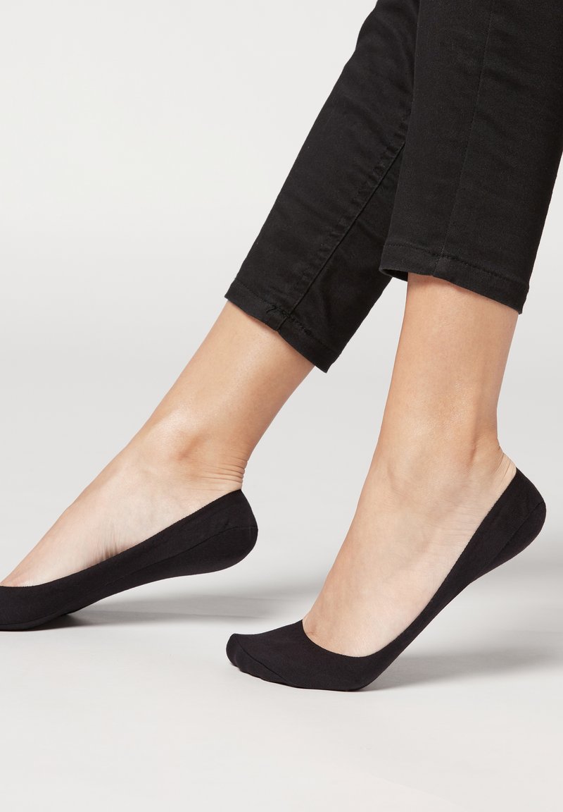 Schwarze Ballerinas mit einem weichen Stofffinish. Rundspitzendesign, tiefe Seiten und eine leichte Konstruktion. Getragen mit schwarzen cropped Hosen.
