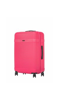 Jasnoróżowa walizka z twardą skorupą, poziome żłobienia, czarne uchwyty oraz cztery czarne obrotowe kółka.