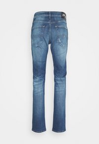 Niebieskie dżinsy z prostymi nogawkami, lekko sprane, z dwoma tylnymi kieszeniami i metką z logo na pasie.