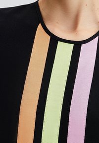 Top nero con righe verticali in tessuto a costina arancione, verde, rosa e viola. Il colletto è rotondo e ha una finitura liscia.