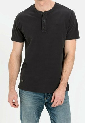 T-shirt noir à manches courtes avec un motif texturé, un col rond et une patte de boutonnage à deux boutons. Associé à un jean en denim bleu.