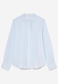 Blouse bleu clair à manches longues avec col rond, fermeture boutonnée devant et plis verticaux subtils sur la poitrine.