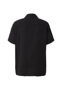 Chemise noire à manches courtes avec un motif chevron subtil, col classique et un petit détail en boucle dans le haut du dos.