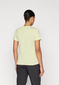 Ανοιχτό κίτρινο κοντομάνικο μπλουζάκι με στρογγυλή λαιμόκοψη και λεία υφή, εμφανιζόμενο από πίσω με ελάχιστη λεπτομέρεια ραφής.