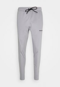 Grå mjuka joggers med elastisk midja och dragsko, smalnande ben, slät textur och en diskret logotyp på vänster lår.