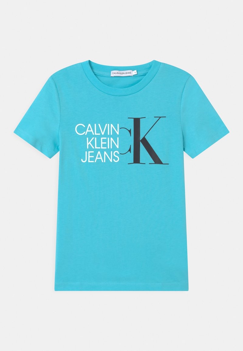 Turkusowa bawełniana koszulka z krótkim rękawem, z graficznym nadrukiem "CALVIN KLEIN JEANS" oraz wyraźnym czarnym "K" z przodu.