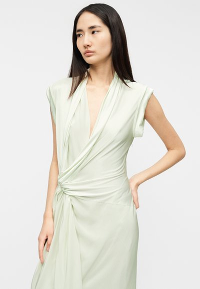 Robe portefeuille vert clair à manches courtes, avec un détail torsadé à la taille et un décolleté en V profond. Tissu lisse et léger.