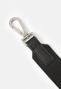 Zwarte stoffen band met een glad leren bevestiging en een zilveren metalen clip. De clip heeft een afgeronde bovenkant en een vergrendelmechanisme.