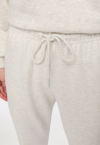 Jasnoszare dresy wykonane z miękkiej, teksturowanej tkaniny, z elastycznym pasem w talii i sznurkiem do regulacji dopasowania.