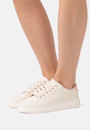 Helle beigefarbene Sneakers mit einer glatten Textur, rosa Akzenten an der Ferse und einer abgerundeten Spitze. Sie verfügen über eine Schnürung und dezente Markenkennzeichnung.