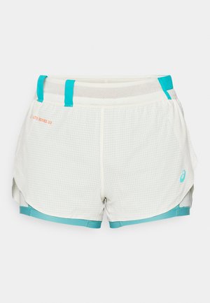 Lightweight, mesh-lined shorts in white with turquoise accents. Features grid pattern, drawstring waist, and side slits for mobility.