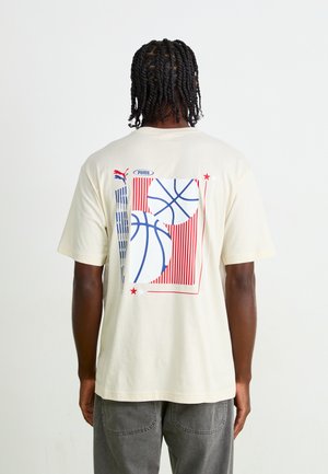 Cream cotton t-shirt featuring a graphic of basketballs in blue and red, with vertical stripes and stars on the back.