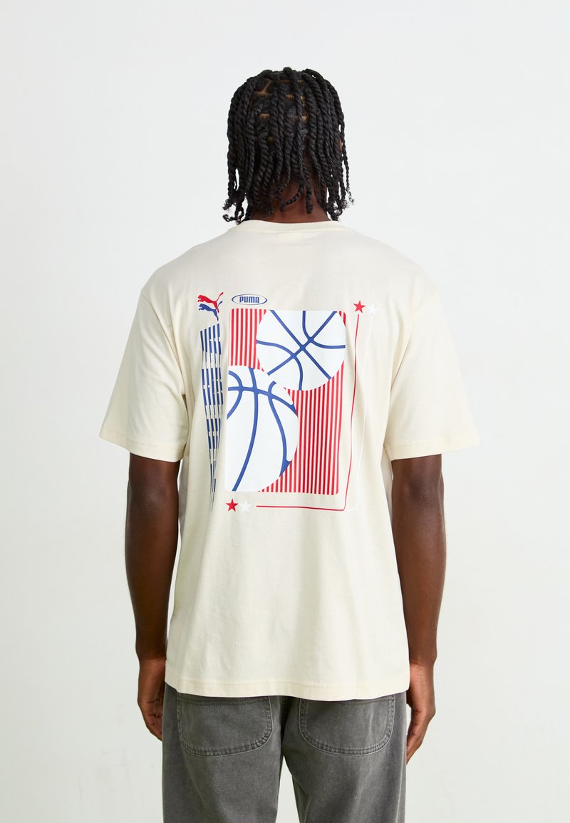 Cream cotton t-shirt featuring a graphic of basketballs in blue and red, with vertical stripes and stars on the back.