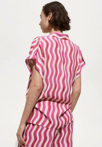 Pink and white short-sleeve shirt with wavy pattern, featuring a collared neckline and button accents. Lightweight fabric.