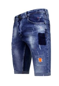 Donkerblauwe denimshorts met een gescheurd uiterlijk. Bevat patches, rafelige randen en verfvlekken. Knie-lange snit met vijf zakken.