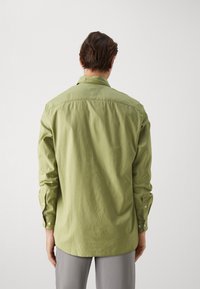 Camicia a maniche lunghe in cotone verde chiaro, con colletto classico, polsini con bottone e orlo arrotondato. Tessuto liscio e vestibilità casual.
