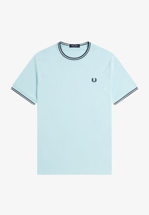 T-shirt bleu clair à manches courtes avec des doubles rayures noires sur le col et les manches, arborant un petit logo en forme de couronne de laurier noire sur la poitrine.