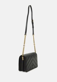 Borsa a mano in pelle nera con un design a zigzag trapuntato. Presenta una tracolla a catena con un accento dorato e una chiusura a patta.