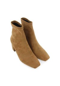 Bottines en daim beige avec un orteil carré, un talon bloc et des détails de couture doublés. Design minimaliste sans accents matériels visibles.