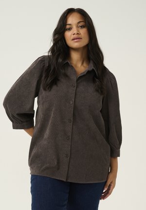 Dark gray button-up shirt with a collar, rounded hem, and balloon sleeves. Made of textured fabric with subtle patterns, worn with blue jeans.