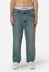 Džíny z lehce opraného denimu s rovnými nohavicemi, mají pět kapes, poutka na pásek a vybledlou texturu. Bílý pas s logem "PEGADOR".