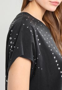 Czarny t-shirt z krótkim rękawem, wykonany z miękkiej bawełny, ozdobiony rozmieszczonymi na tkaninie błyszczącymi cyrkoniami.