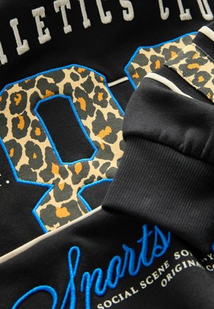 Sweatshirt noir avec un grand numéro "88" en motif léopard, bordé de bleu. Le texte "Athletics Club" et "Sports" est en blanc et bleu.