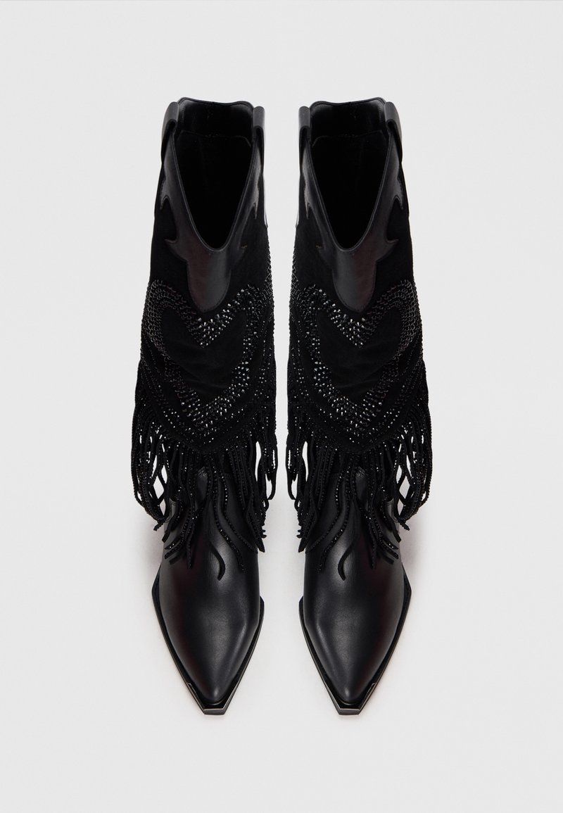 Stivali alla caviglia in pelle nera con punte affusolate, decorati con frange in suede nero e dettagli di perline ai lati.