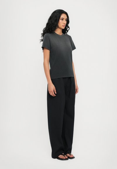 Black cotton t-shirt with short sleeves, paired with loose-fitting black trousers. Smooth texture, simple design, and no patterns.