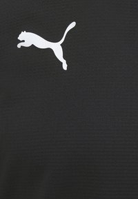 Czarna tkanina o teksturowanym wykończeniu z wyraźnym białym logo Pumy przedstawiającym skaczącą kotkę umieszczonym po lewej stronie.