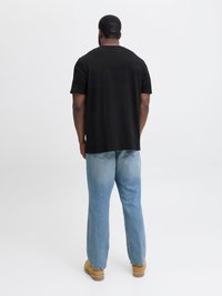 Černé tričko s krátkým rukávem spárované se světle modrými denimovými džínami. Džíny mají uvolněný střih s jemným vyblednutím a klasickým pěti-kapsovým designem.