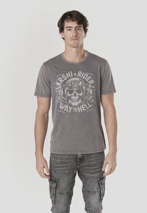 Camiseta de algodón gris con un gráfico de calavera, texto "KASHI RIDER WAY TO HELL" y cuello redondo. Detalles visibles de costura.