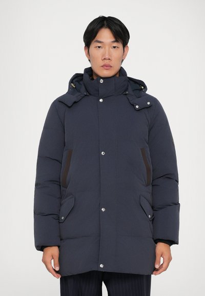 Giubbotto invernale blu scuro con colletto alto, cappuccio con zip e chiusure a pressione. Presenta tasche laterali marroni e un design snello e imbottito.