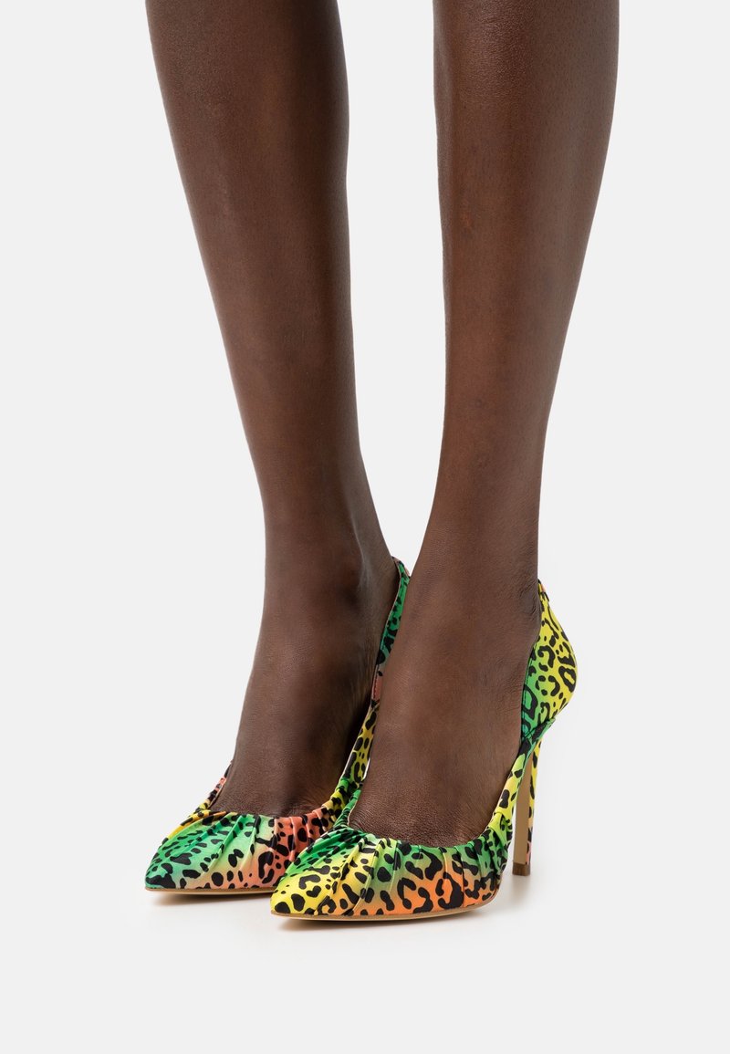 Des chaussures à talons hauts colorées avec un bout pointu, arborant un motif léopard vibrant dans des teintes vertes, jaunes, oranges et noires.
