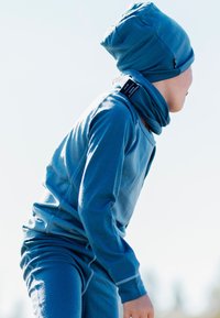 Blue thermal outfit with a long-sleeve top, matching scarf, and beanie. Smooth texture and fitted design with slight gathering at edges.