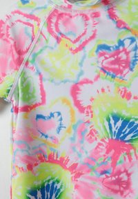 Vícebarevný, krátký rukáv rash guard z lehké, elastické tkaniny má barevný tie-dye vzor v růžové, zelené a modré na bílém pozadí.