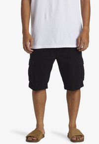 Zwarte cargoshorts met twee zijzakken, een knielange snit en een katoenmix stof, gecombineerd met bruine slide-sandalen.