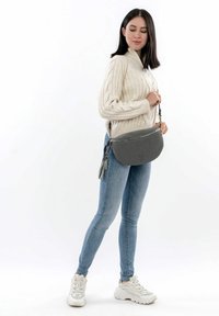 Borsa a tracolla grigia con forma arrotondata, finitura testurizzata e chiusura a zip. Presenta un tassello decorativo e una tracolla regolabile.