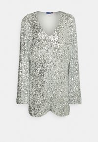 Stříbrný top s flitry, s hlubokým výstřihem do V, dlouhými rukávy a mírným zakřivením na spodním lemu. Má lesklý, strukturovaný povrch.